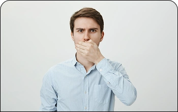 Man covering his mouth with his hand, illustrating concerns with bad breath (halitosis)